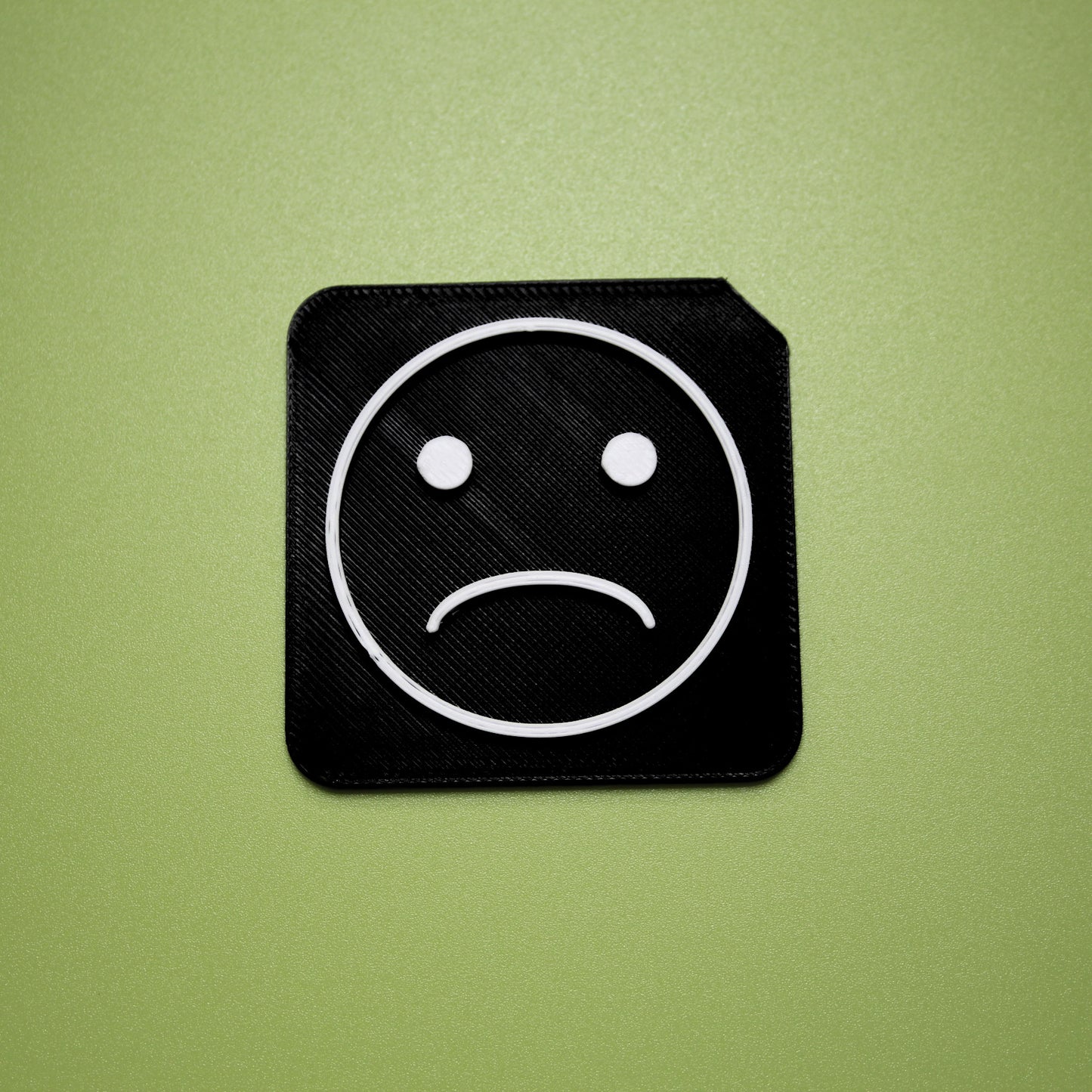 Sad tactile tile - 3D printed raised symbol showing sad face for AAC and SEND communication