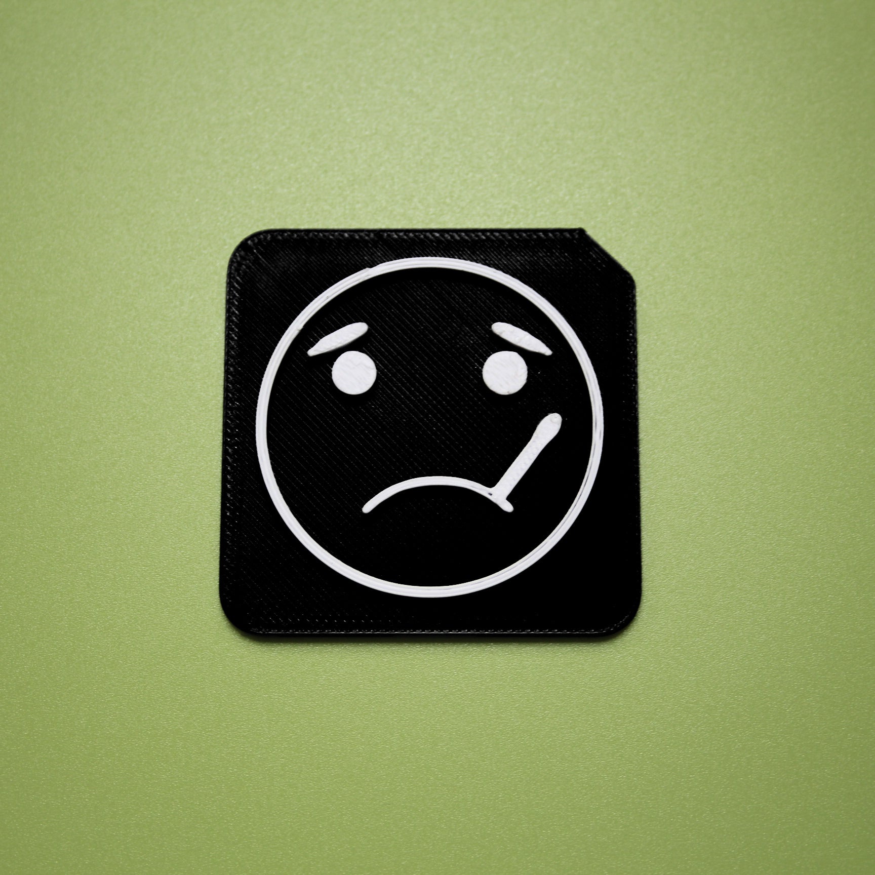 Sick tactile tile - 3D printed raised symbol showing sick face for AAC and SEND communication