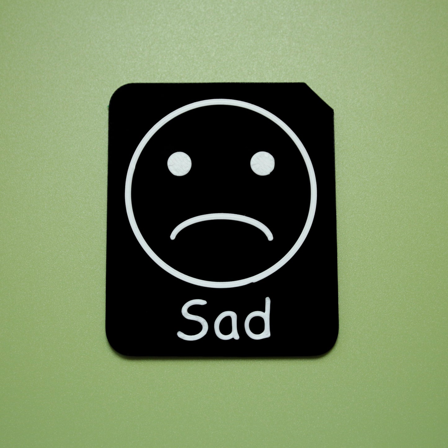 Sad tactile tile - 3D printed raised symbol showing tired face for AAC and SEND communication with vocabulary