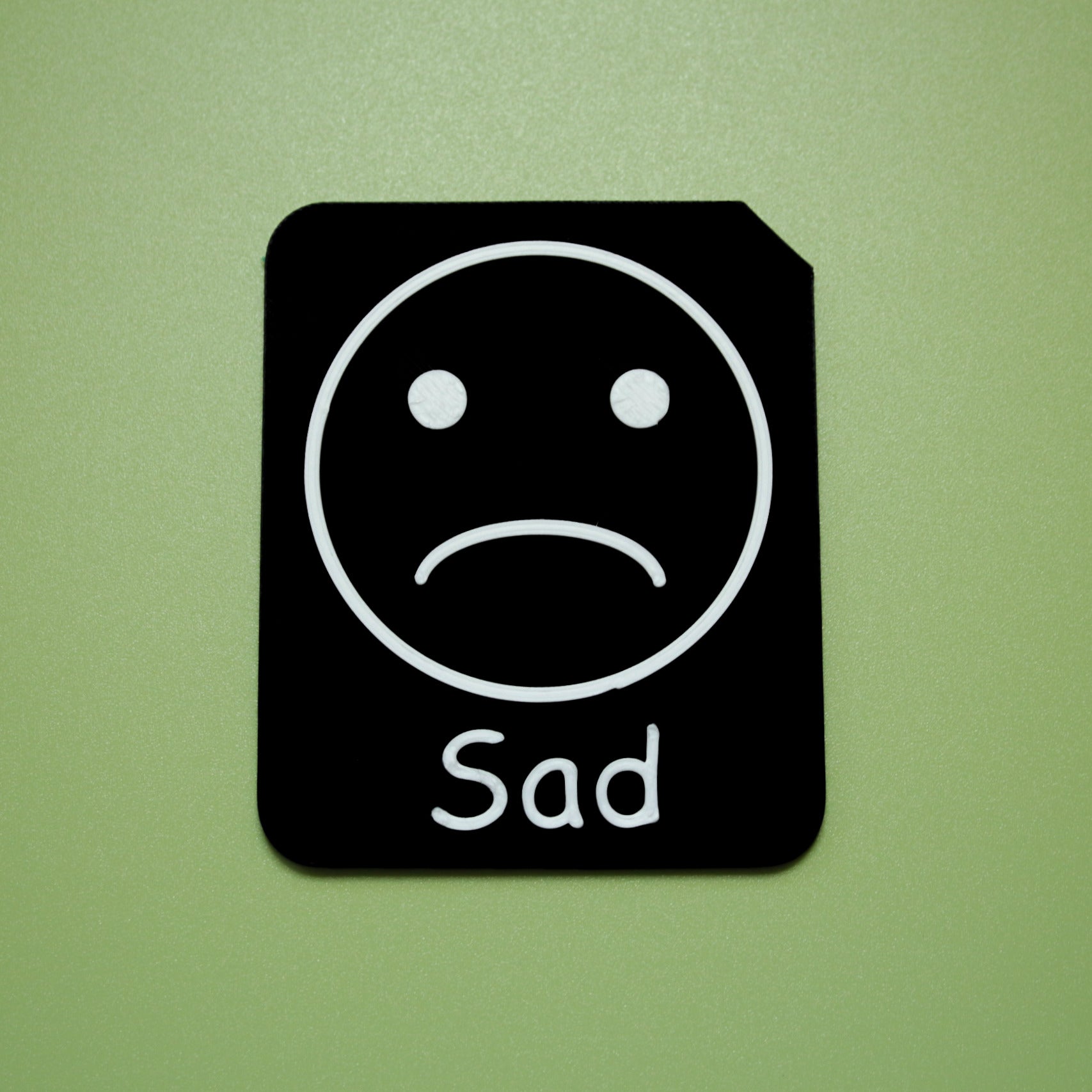 Sad tactile tile - 3D printed raised symbol showing tired face for AAC and SEND communication with vocabulary