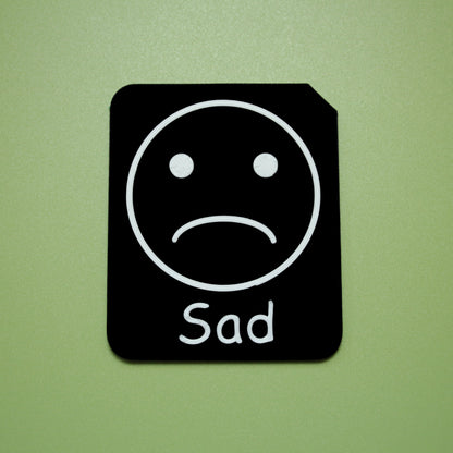 Sad tactile tile - 3D printed raised symbol showing tired face for AAC and SEND communication with vocabulary