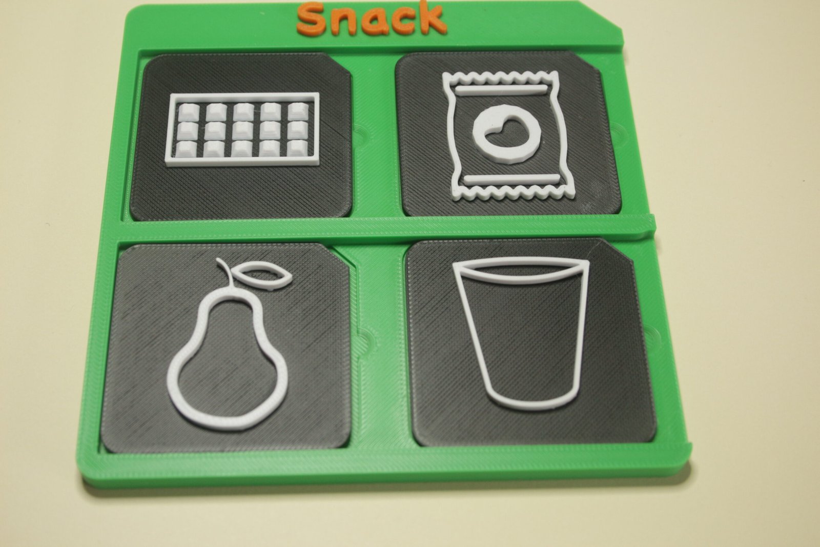 Tactile AAC symbols displaying food options on a 3d printed snack choice board.