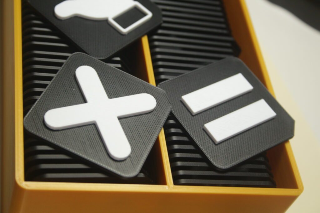 Image of AAC tactile tiles showing 'No' indicated by a cross and 'pause' indicated by a 3d printed pause logo (two vertical lines)